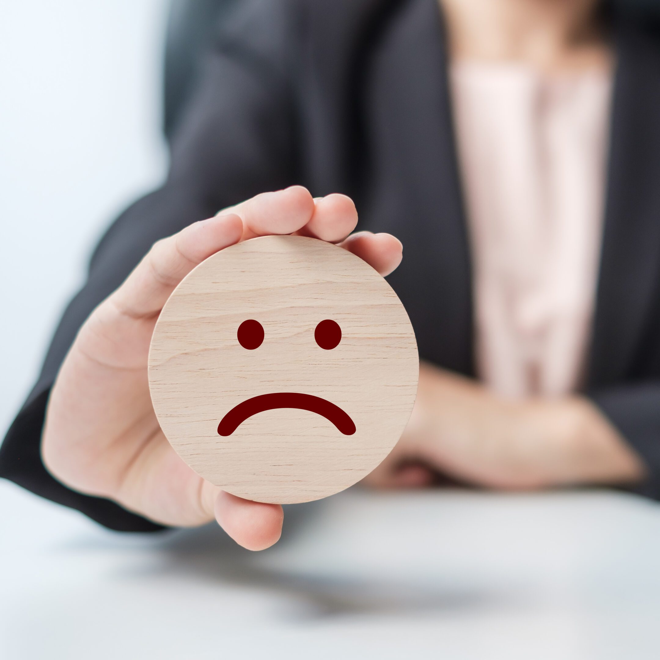 hand holding angry face block. Customer choose Emoticon for user reviews. Service rating, ranking, customer review, satisfaction, mood, mental health and feedback concept